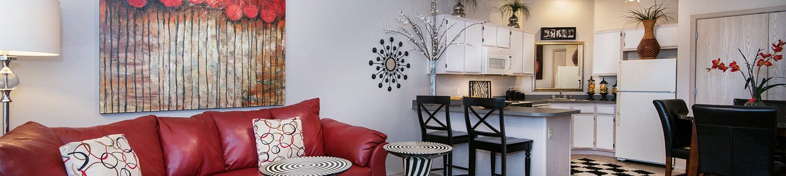 a living room with a red couch and a kitchen with a counter